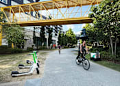 Thumbnail 39 of 42 - A person riding a bike under a yellow bridge in a park. at West Inman Lofts, Atlanta, Georgia
