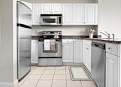 Thumbnail 1 of 10 - A kitchen with white cabinets and appliances.