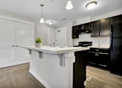 Thumbnail 10 of 25 - A kitchen with white cabinets and a black refrigerator.