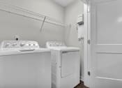 Thumbnail 23 of 25 - Two white washing machines in a laundry room.