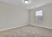 Thumbnail 11 of 25 - A room with a carpeted floor and a window with blinds.