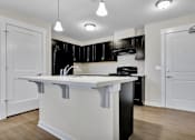 Thumbnail 3 of 25 - A kitchen with black cabinets and white countertops.