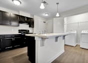 Thumbnail 4 of 25 - A kitchen with black cabinets and white appliances.