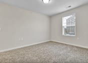 Thumbnail 19 of 25 - A room with a carpeted floor and a window with blinds.