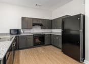 Thumbnail 14 of 22 - A kitchen with black cabinets and a black refrigerator.