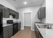 Thumbnail 16 of 22 - A kitchen with black cabinets and a white door.