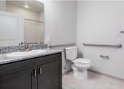 Thumbnail 19 of 22 - A white toilet sits in a bathroom next to a sink and a towel bar.