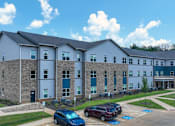 Thumbnail 6 of 22 - A large building with a parking lot in front of it.