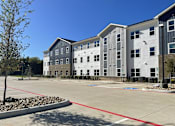 Thumbnail 8 of 22 - A parking lot in front of a building with a red line painted on the ground.