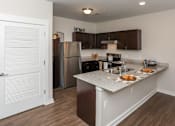 Thumbnail 12 of 22 - A kitchen with a refrigerator, sink, and cabinets.