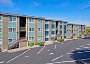 Thumbnail 8 of 14 - Outside apartments with numbered parking spots and well-maintained landscaping.