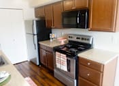 Thumbnail 17 of 19 - a kitchen with stainless steel appliances and brown wooden cabinets at Heritage Grove Apartments in Renton, WA