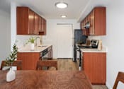 Thumbnail 7 of 19 - A kitchen with brown wooden cabinets and a white door at Heritage Grove Apartments in Renton, WA