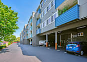 Thumbnail 10 of 14 - Apartments with carports, access to the leading office to the right, and mailboxes and trees on the left.