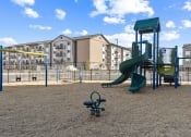 Thumbnail 18 of 36 - a playground with a slide and swings in front of an apartment building at Yellowstone Landing, Montana, 59714