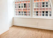 Thumbnail 3 of 14 - Empty bedroom with arched windows and hardwood floors at Textile Lofts Apartments, Ohio