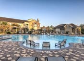 Thumbnail 11 of 38 - a large swimming pool with patio furniture in front of a house at Waterstone at Cinco Ranch, Katy