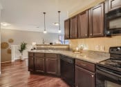 Thumbnail 75 of 84 - a kitchen with wooden cabinets and a counter top  at Grand Villas Apartments, Texas