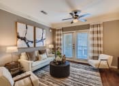 Thumbnail 67 of 84 - a living room with a couch and a ceiling fan  at Grand Villas Apartments, Texas