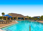 Thumbnail 47 of 84 - a swimming pool with chairs and umbrellas at the club house at Grand Villas Apartments, Katy