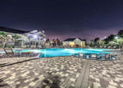 Thumbnail 19 of 38 - a large swimming pool at night with chairs around it  at Waterstone at Cinco Ranch, Katy, TX, 77450