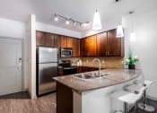 Thumbnail 31 of 43 - a kitchen with a granite counter top and a stainless steel refrigerator at Discovery at Craig Ranch, McKinney, TX