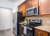 Thumbnail 32 of 43 - a kitchen with stainless steel appliances and wooden cabinets at Discovery at Craig Ranch, McKinney, TX