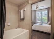Thumbnail 36 of 43 - a bathroom with a tub and a bedroom with a bed at Discovery at Craig Ranch, Texas