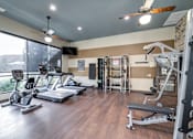 Thumbnail 48 of 59 - A gym with a variety of equipment including treadmills, weights, and a ceiling fan.