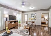 Thumbnail 4 of 47 - A living room with a television, a dining table, and chairs at Avenues at Shadow Creek Ranch Apartments, Pearland, TX
