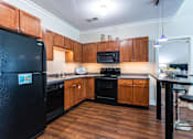 Thumbnail 1 of 57 - A kitchen with wooden cabinets and black appliances. at CityView, North Kansas City, Missouri