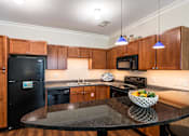 Thumbnail 9 of 57 - A kitchen with wooden cabinets and a black fridge. at CityView, North Kansas City, Missouri