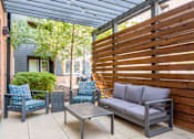 Thumbnail 23 of 101 - A patio with a grey couch, two chairs and a table.