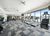 Thumbnail 18 of 84 - the state of the art fitness room with floor to ceiling windows and cardio equipment at Grand Villas Apartments, Texas, 77494