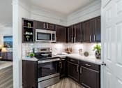 Thumbnail 9 of 47 - Kitchen with dark brown cabinets at Grand Villas at Cinco Ranch, Katy, TX, 77494