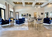 Thumbnail 6 of 38 - a living room with blue chairs and tables and a kitchen at Waterstone at Cinco Ranch, Katy, TX, 77450