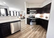 Thumbnail 3 of 84 - a kitchen with black cabinets and stainless steel appliances at Grand Villas Apartments, Katy