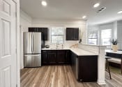 Thumbnail 1 of 84 - a kitchen with black cabinets and a stainless steel refrigerator at Grand Villas Apartments, Katy