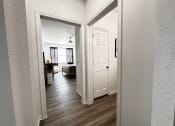 Thumbnail 30 of 84 - a view of the living room from the hallway with the bedroom door open at Grand Villas Apartments, Katy
