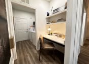 Thumbnail 31 of 84 - a home office with a desk and a door to a kitchen at Grand Villas Apartments, Katy