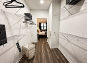 Thumbnail 37 of 84 - a walk in closet with shelves and a basket on the floor at Grand Villas Apartments, Katy