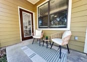 Thumbnail 29 of 84 - a front porch of a home with two chairs and a table at Grand Villas Apartments, Katy