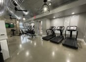 Thumbnail 19 of 63 - a gym with treadmills and other exercise equipment in a building with glass doors at Edge 35, Indianapolis