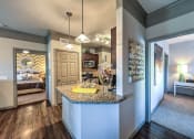 Thumbnail 31 of 38 - a kitchen with a granite counter top and a door to a bedroom  at Waterstone at Cinco Ranch, Katy, Texas