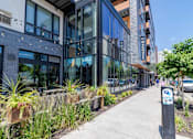 Thumbnail 75 of 77 - A modern building with a glass facade and a parking sign on the sidewalk.