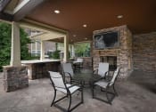 Thumbnail 33 of 39 - a covered patio with a table and chairs and a fireplace at Sovereign at Overland Park, Kansas