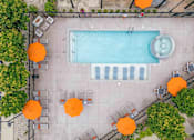 Thumbnail 24 of 59 - An aerial view of a pool surrounded by orange umbrellas and chairs. at Penn Circle, Carmel, IN
