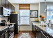 Thumbnail 2 of 59 - A kitchen with black cabinets and granite countertops. at Penn Circle, Carmel