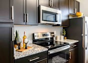 Thumbnail 4 of 59 - A modern kitchen with a black refrigerator, microwave, and stove. at Penn Circle, Carmel, Indiana