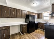 Thumbnail 3 of 43 - A kitchen with wooden cabinets and a black fridge at Spring Creek Townhomes Apartments, Springfield